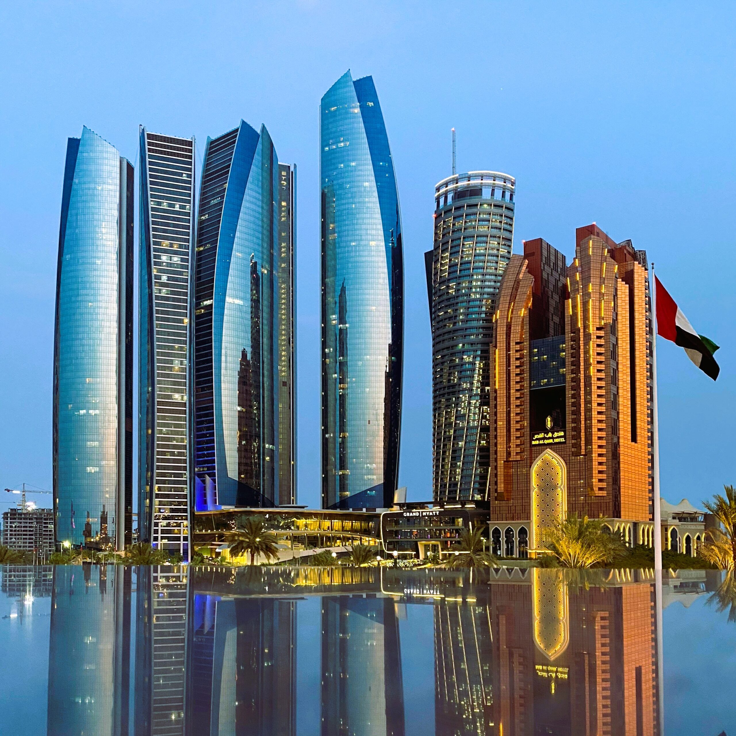 Etihad Towers Abu Dhabi skyline with reflection in water at dusk