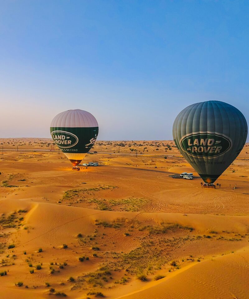 Hot air balloon flying over Dubai desert dunes at sunrise